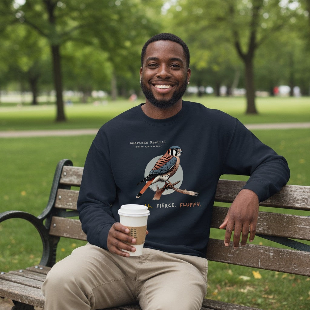 Navy blue unisex bird sweatshirt with the words, "Small. Fierce. Fluffy" below an illustration of an American Kestrel. Worn by a man.