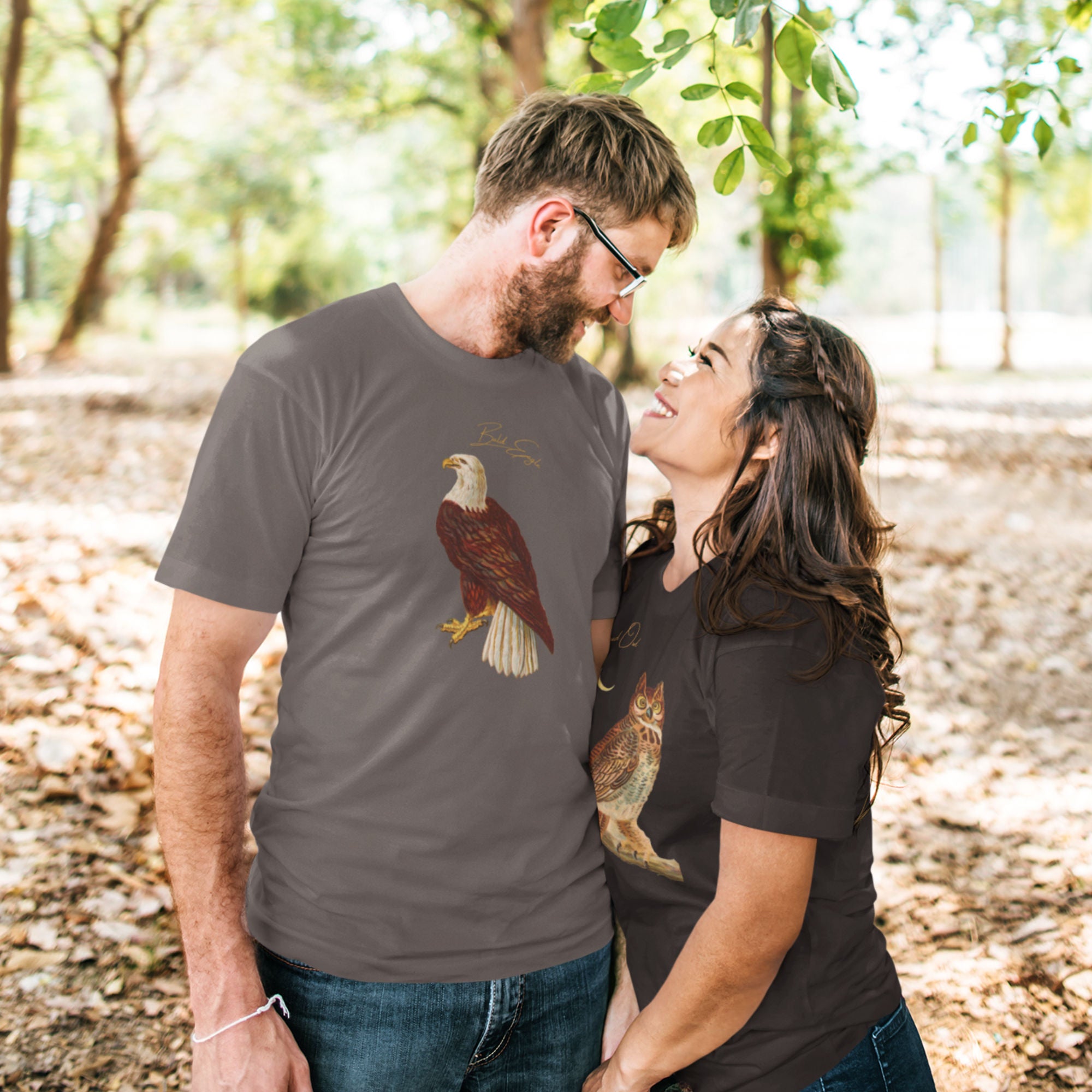 Dark gray bird shirt with vintage artwork of a bald eagle and the words "Bald Eagle" centered above the art. Worn by a man in the park with his girlfriend.