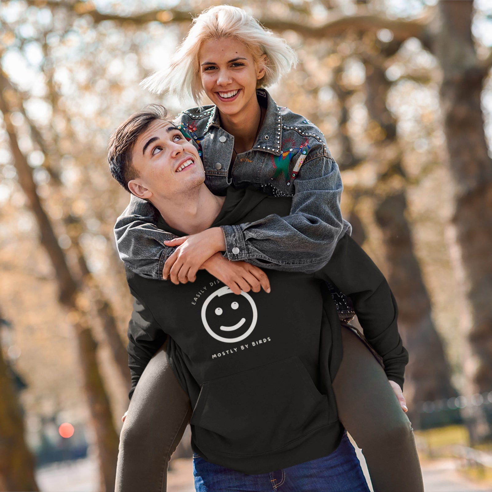 Black hoodie with a smiley face looking off to the right at a flock of birds and the words Easily Distracted, Mostly By Birds on the front.