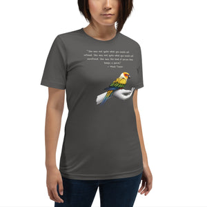 Unisex dark gray  t-shirt with a sun conure on a hand and a Mark Twain quote about a woman who keeps parrots. Worn by a woman.