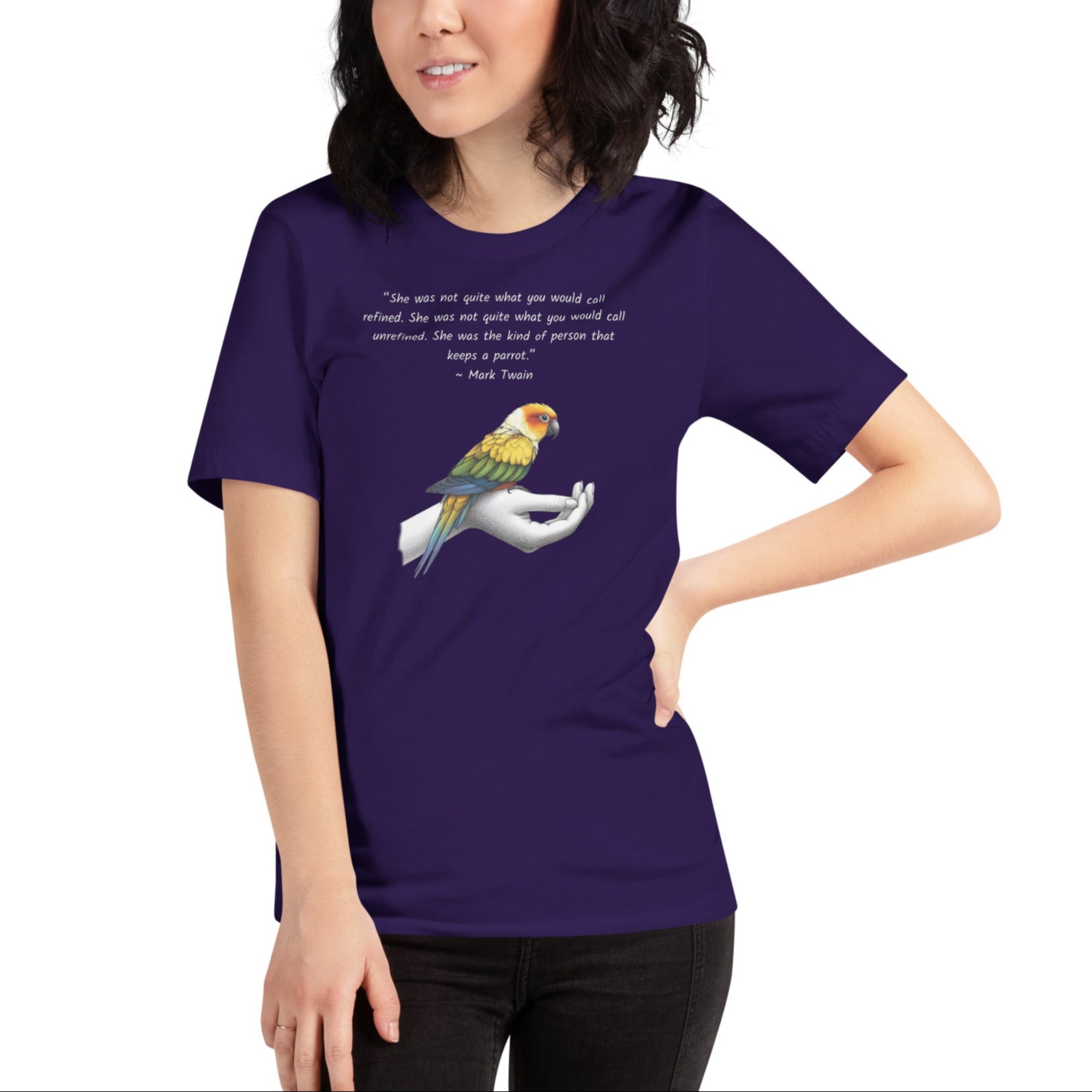 Unisex deep purple  t-shirt with a sun conure on a hand and a Mark Twain quote about a woman who keeps parrots. Worn by a woman.