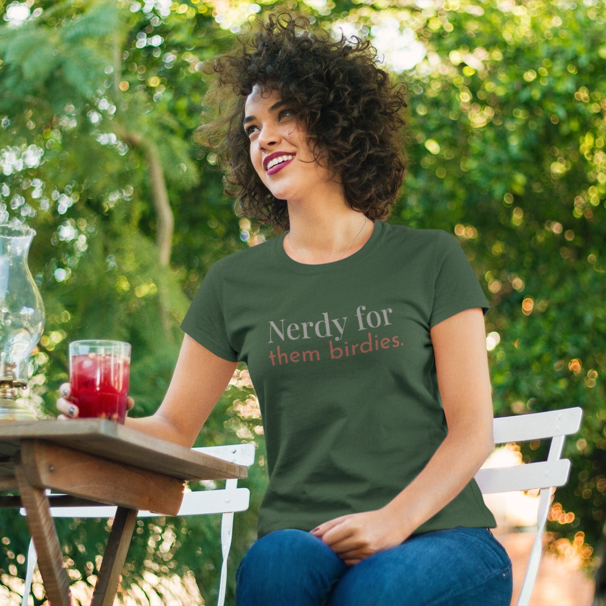 Forest green unisex bird shirt with the words Nerdy for them birdies on the front in two coordinating fonts and colors. Worn by a woman.