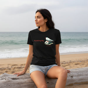 Woman sitting on a beach wearing a women's relaxed crew neck birding tee in black with an arctic tern design.