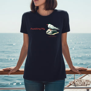 Person wearing a navy t-shirt with a arctic tern graphic and text, standing on a boat, on the sea.