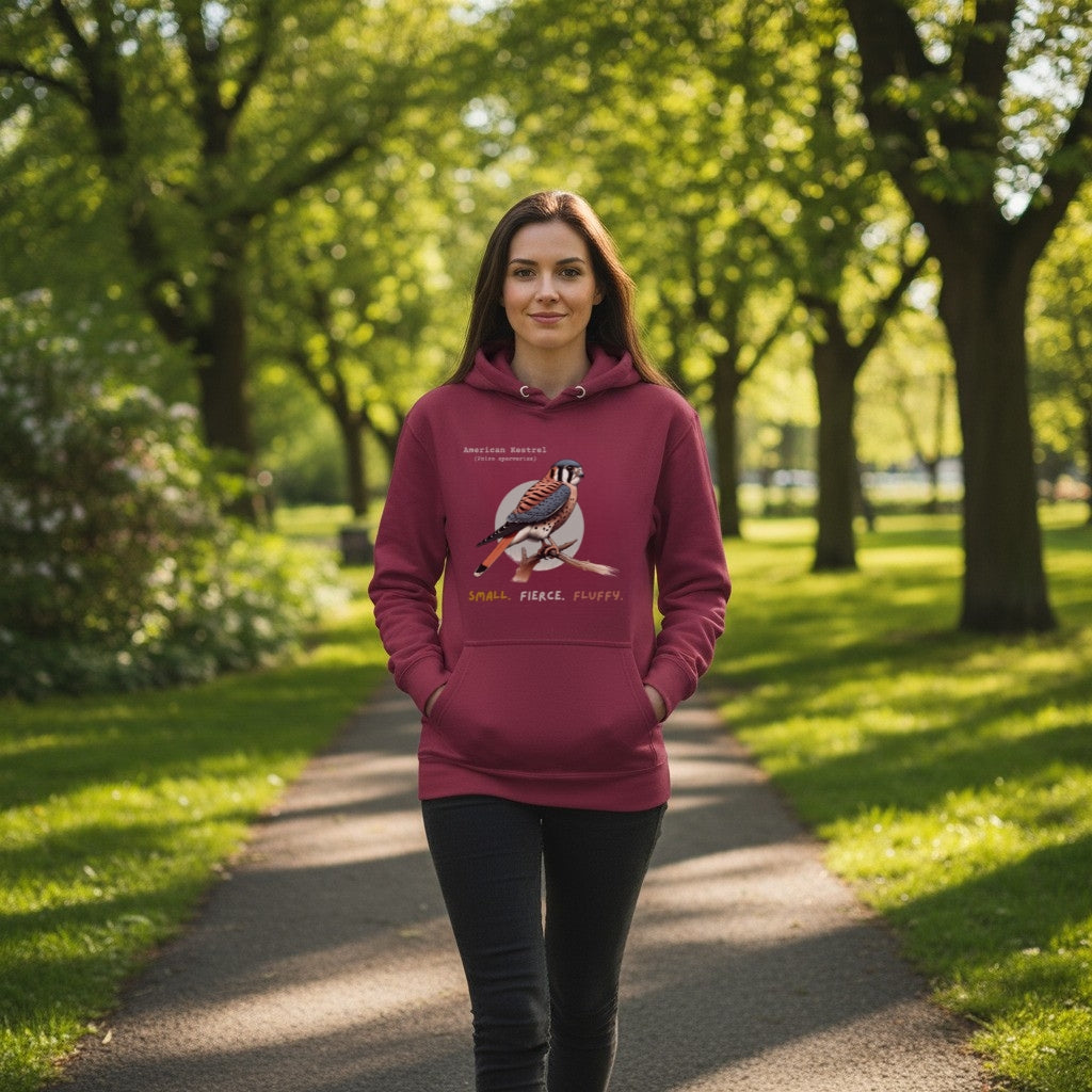 Maroon hooded unisex bird sweatshirt with the words, "Small. Fierce. Fluffy" below an illustration of an American Kestrel.  Worn by a woman.