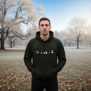Unisex black hooded bird sweatshirt celebrating bird watching and coffee with a graphic of binoculars, a bird, and a travel cup of coffee. Worn by a man standing in a cold looking park.