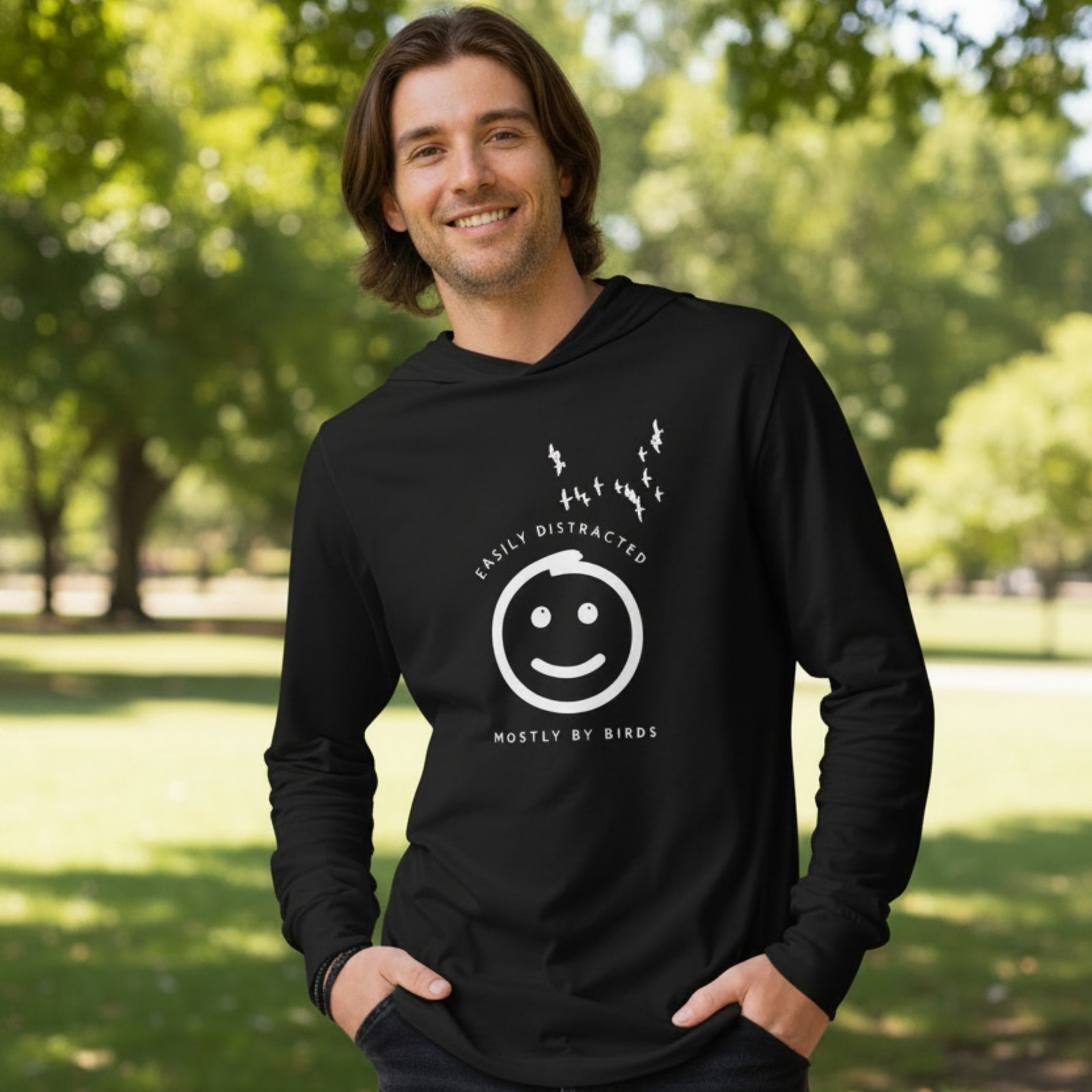 Black long sleeved and hooded tee with fun, "Easily Distracted, Mostly by Birds" saying on the front, with a smiley face looking up at a flock of birds.