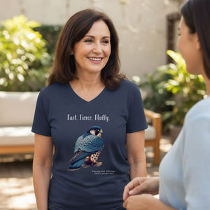 Heather navy women's v-neck bird t-shirt with the words, Fast. Fierce. Fluffy. and a peregrine falcon graphic below. Worn by a woman speaking with another woman on a patio.