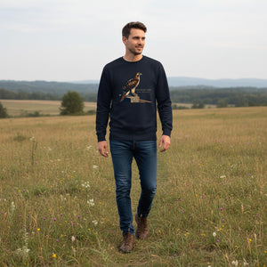 Navy birding sweatshirt with an artistic depiction of a red-tailed hawk sitting on a fence and the common and scientific names for the bird next to it. Worn by a man walking in a field.