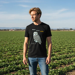 Man wearing a black t-shirt with a snowy owl graphic in a field