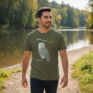 Man wearing a green t-shirt with a snowy owl design by a river