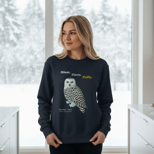 Woman wearing a navy sweatshirt with a snowy owl design and text in a kitchen on a snowy day.