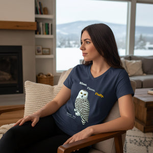 Woman wearing a navy blue t-shirt with a snowy owl design and text, sitting in a cozy living room.