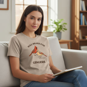 Heather tan women's relaxed fit bird shirt with a male and female northern cardinal and the words, "Will Brake for Gingers" worn by a woman sitting on a couch.