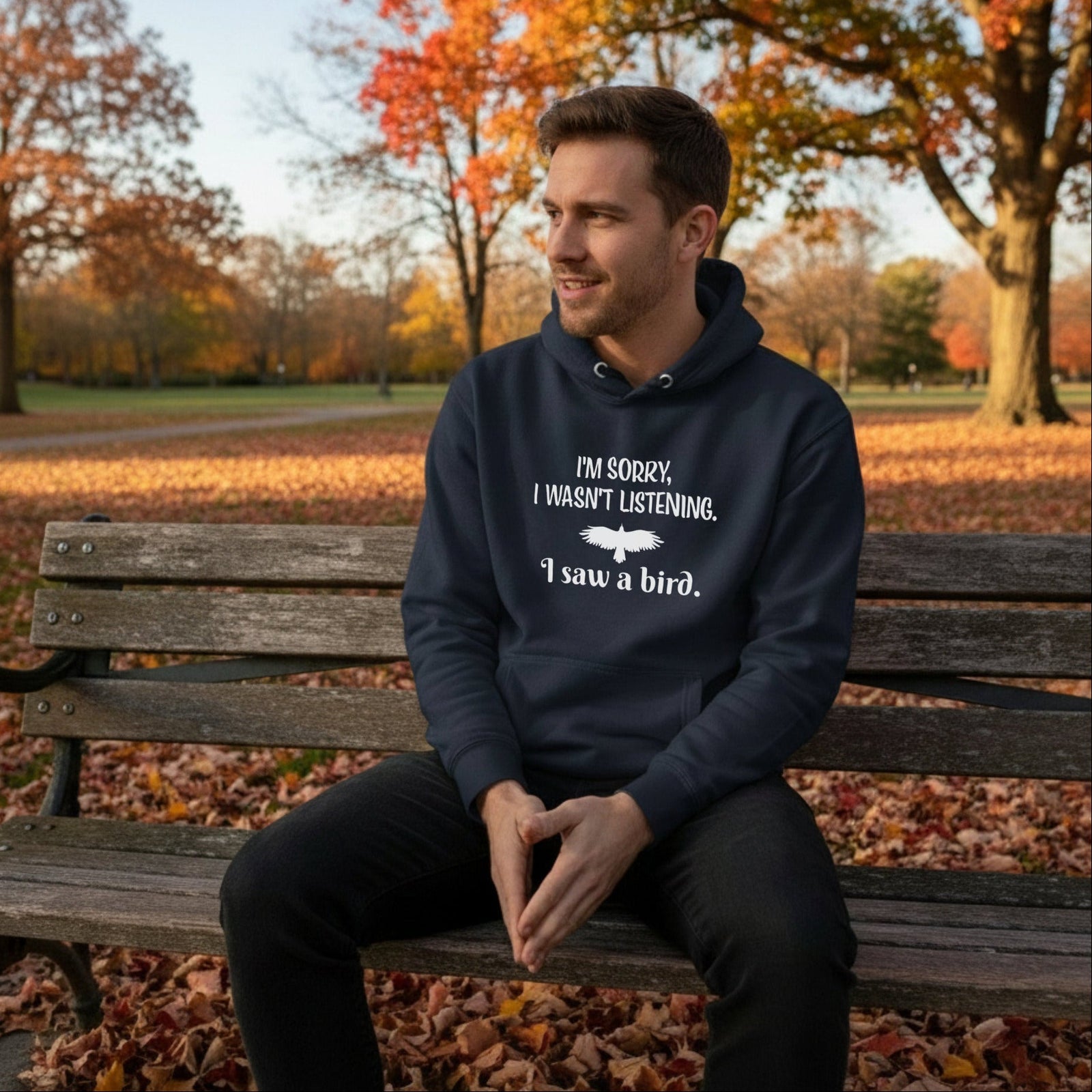 Navy unisex bird hoodie with the words I'm sorry I wasn't listening, I saw a bird. And a graphic of a bird flying. Worn by a man.