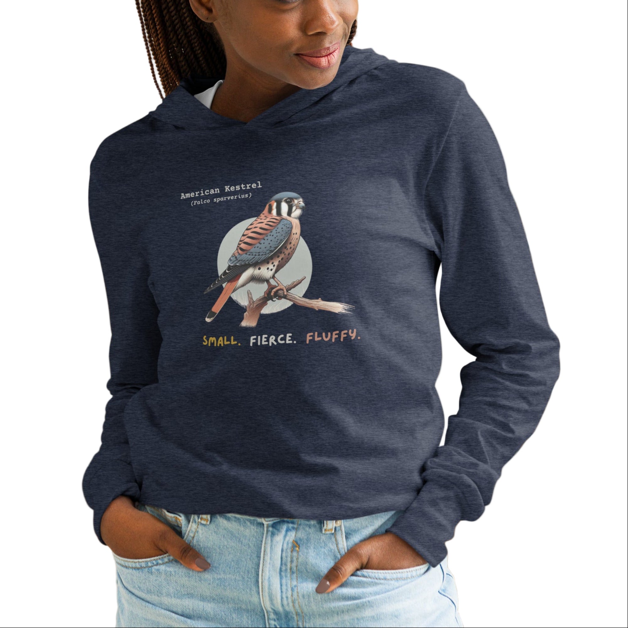 Heather navy long sleeved and hooded unisex bird shirt with the words, "Small. Fierce. Fluffy" below an illustration of an American Kestrel.  Worn by a woman.